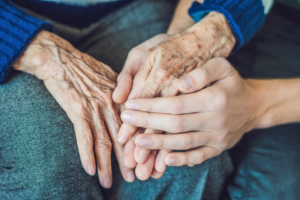 patient and nurse holding hands in gesture of comfort