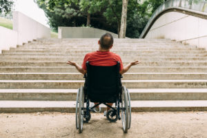 disabled man on wheelchair stopped outraged in front of stairs who can't climb looking for help, raising awareness of architectural barriers and accessibility issues for people with reduced mobility