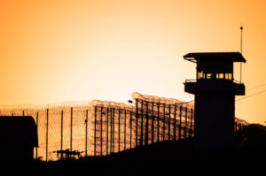 Silhouette of barbed wires and watchtower of prison.