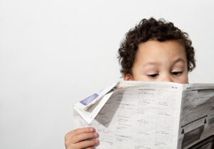 Little boy reading newspaper and smiling in the morning been educated with white background stock photo