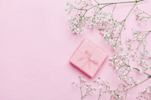 Gift or present box and flower on pink table from above. Pastel color.