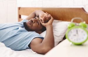 Bad mood in morning. Overslept black guy lying in bed and conteplaining, closeup