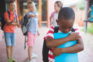 School friends bullying a sad boy in corridor at school