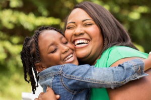 African American mother and daughter laughing and hugging each other.