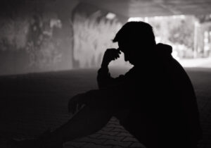 depressed young man sitting down on ground