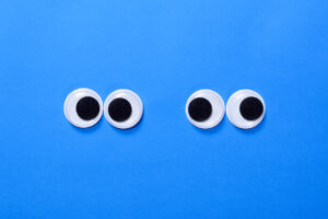 Googly eyes: Two pair strabismus and squint mad googly eyes next to each other on blue background.