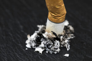 Stubbed cigarette butt stub with ash on black background