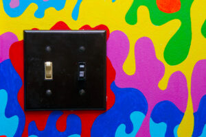 A plastic, interior double lightswitch mounted on a funky colored, painted wall.