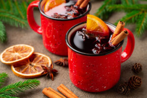 Two cups of christmas mulled wine or gluhwein with spices and orange slices on rustic table top view. Traditional drink on winter holiday.