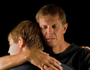 Father cries as he hugs his teenage son