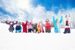 Large group of diversity looking kids boys and girls throwing snow in the air together sitting in a row