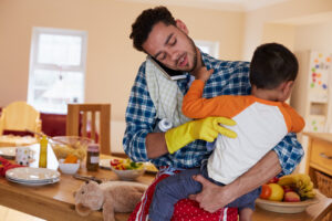 Busy Father Looking After Son Whilst Doing Household Chores