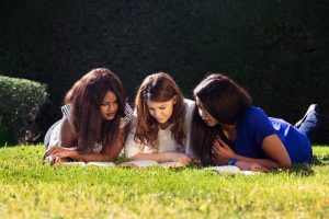3 teens reading outside