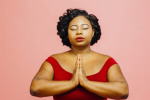 Inner peace/ Young woman in red with eyes closed and hands together
