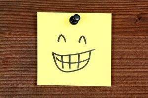 Sticky note with smiley happy face. Bulletin board.