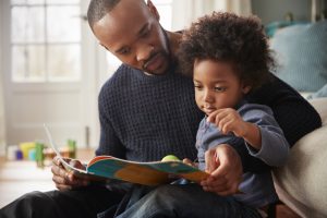 father and toddler reading together