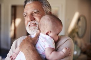 Hispanic grandfather holding his baby grandson, head and shoulders, close up