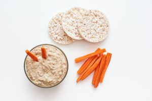 Only useful snack. Hummus with carrot sticks. Top view of humus with loaves of food balance isolated on white background.