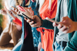 Millennial generation. Colorful cropped closeup of young people holding smartphones. Modern devices. Technological progress.