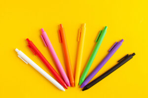 Multi-colored pens on a yellow background. The concept of the beginning of the school year, office supplies, school supplies. High quality photo