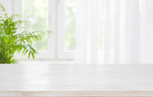Wooden table top on blurred background of half curtained window