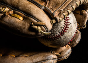 Baseball mitt holding a scuffed up old baseball.