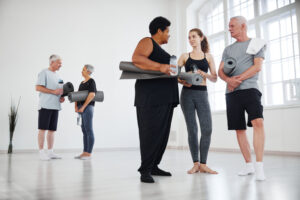 Young instructor giving recommendations to senior people after yoga class in studio