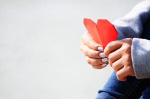 Hands Holding a Red Heart Shape Paper