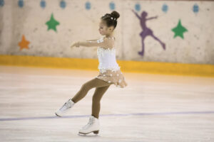 The little skater performs the program. A girl on skates takes part in competitions.