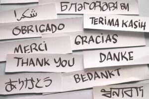 Thank you in different languages, text words typography written on paper against blue background, life and business motivational inspirational concept