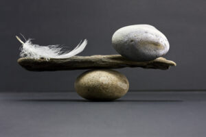 A feather and a stone equally balanced, studio shot with dark lighting set up.