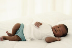 african american newborn infant baby lying on white bed