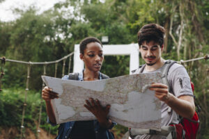 African American woman and a Caucasian man looking at a map together travel and teamwork concept