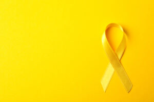 Yellow awareness ribbon on color background, space for text