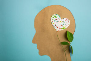 Mental Health Day. Paper Cut as Human Head with Leaf Tree and Colorful Heart Shape Flower inside the Brain.