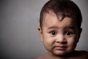 Surprised indian baby boy over dark gray background