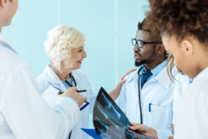 Senior doctor talking to african-american medical intern and touching him on shoulder