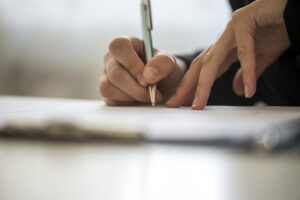 Hands of a person writing on a notepad on a table with copy space.