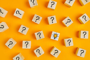 Concept of to find a creative idea or problem solving. Question mark and light bulb icons on wooden cubes on yellow background.