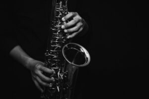 close up of Young Saxophone Player hands playing alto sax musical instrument over a black background, closeup with copy space, vintage tone, can be used for music background