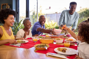 Multi-Generation Family Sitting Around Table At Home Enjoying Meal Together