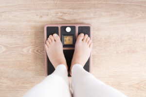 Woman with barefoot standing on the scales. New start for healthy nutrition, body slimming, weight loss. Cares about body concept. Top view.