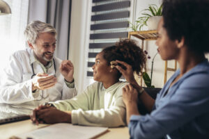 Smiling deaf african american girl with ear implant at doctor's office.