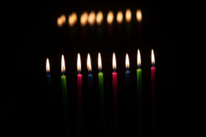 Multi-colored, wax Hanukkah candles burn in a menorah during celebration of the Jewish festival of lights.