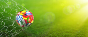 Ball with european flags in the net with green field background