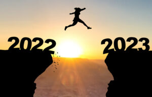 Woman jumps over abyss with sunset in background and inscription 2022 and 2023.