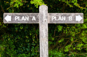 Wooden signpost with two opposite arrows over green leaves background. Plan A versus Plan B directional signs, Choice concept image