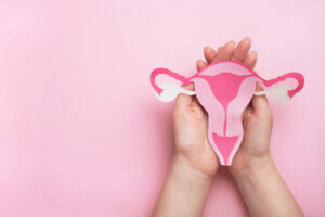 Woman hands holding decorative model uterus on pink background. Top view, copy space