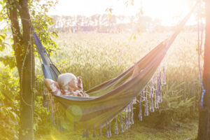 Serene woman napping in hammock next to sunny rural wheat field