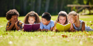 Shot of a group of kids reading a book outside